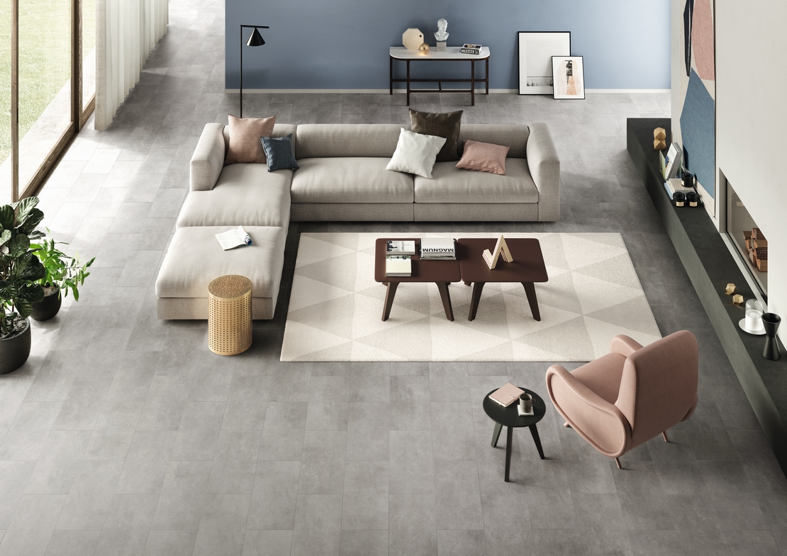 Soggiorno moderno open space, pavimento effetto cemento grigio elegante, toni blu - Ambienti Iperceramica