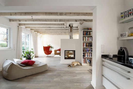 Elegantes, modernes Wohnzimmer mit Kamin und Feinsteinzeug in Steinoptik am Boden