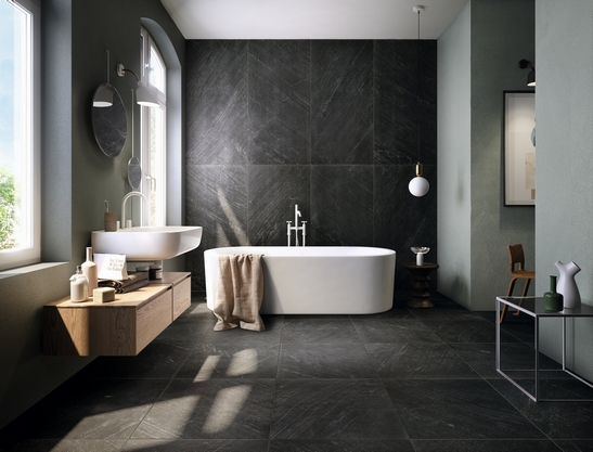 Salle de bains moderne avec baignoire. Effet pierre noire pour une touche classique et de luxe.