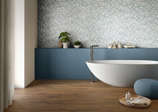Salle de bains moderne colorée avec baignoire, revêtement mural en mosaïque bleue et sol effet bois