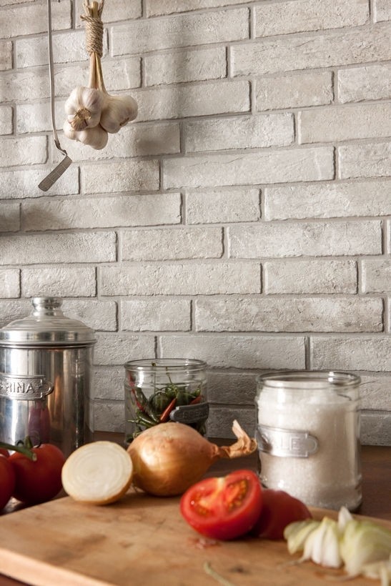 Petite cuisine linéaire vintage avec effet mur en briques et tons de blanc et de gris.
