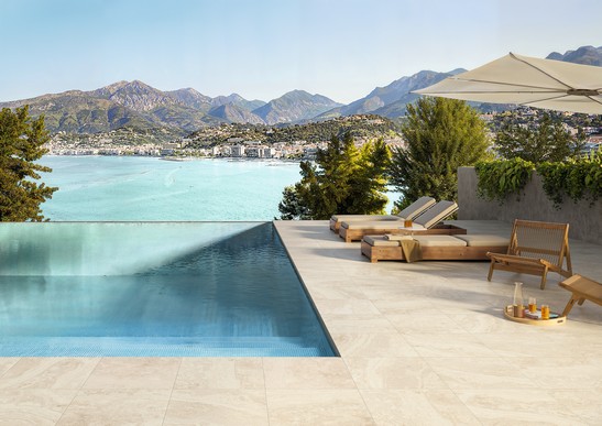 Moderne Terrasse mit beigefarbener Steinoptik Infinity-Pool