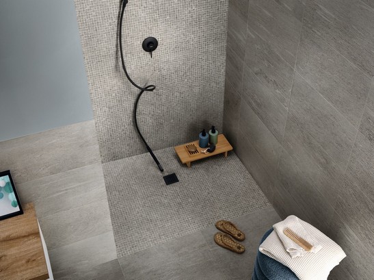 Salle de bains minimaliste style industriel avec douche en mosaïque, revêtement mural et sol imitation pierre 