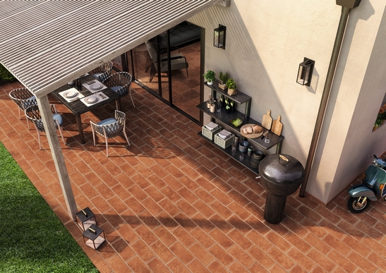 Terrasse couverte rustique/traditionnelle avec sol en grès cérame effet terre cuite aux tons rouges.
