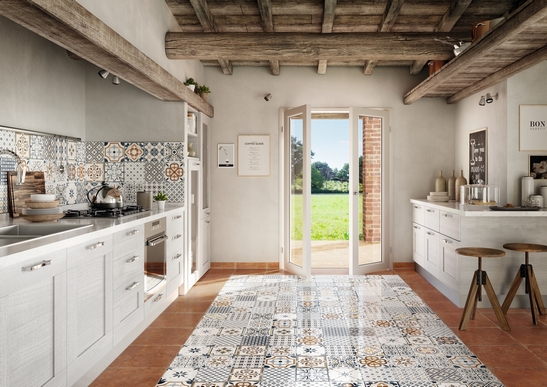 Cuisine moderne avec îlot central : carrelage avec motif gris, bleu et effet terre cuite rouge.