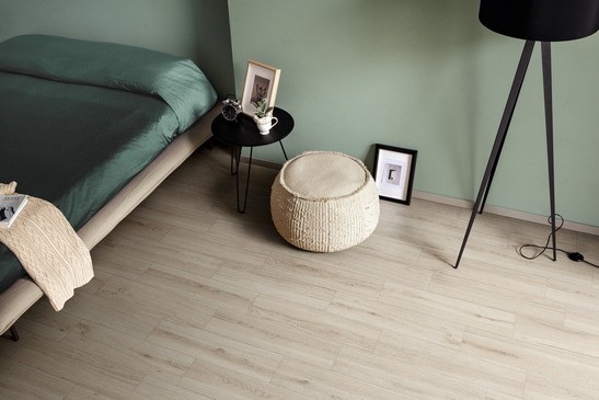 Camera da letto moderna e minimal sui toni del bianco e verde con pavimento in gres effetto legno