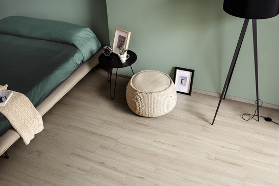 Chambre moderne et minimaliste dans des tons de blanc et de vert avec sol en grès cérame imitation bois