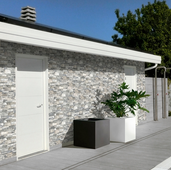 Terrasse avec mur revêtu avec un carrelage imitation pierre naturelle grise pour une touche rustique.