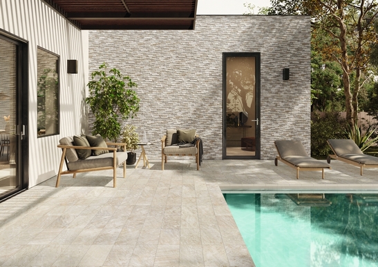 Terrasse moderne bord de piscine, sol en grès cérame effet pierre blanche.