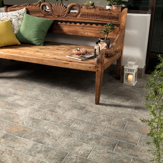 Rustikaler Balkon in warmen Tönen, grauer Feinsteinzeugboden mit Steinoptik