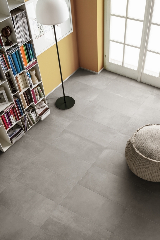 Soggiorno moderno: pavimento gres effetto cemento grigio, toni del giallo per un tocco minimale