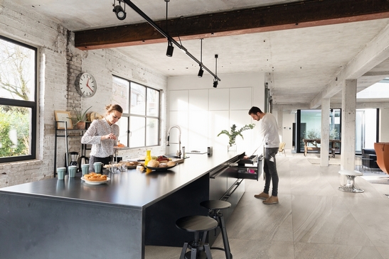 Cuisine moderne ouverte avec îlot central : imitation pierre et tons de gris pour une touche minimaliste et industrielle.