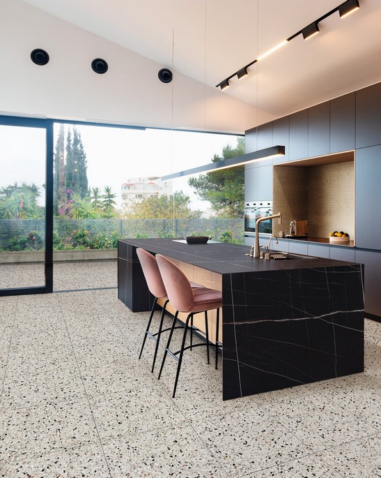 Cuisine ouverte luxueuse, îlot central et revêtement mural effet marbre, sol imitation terrazzo